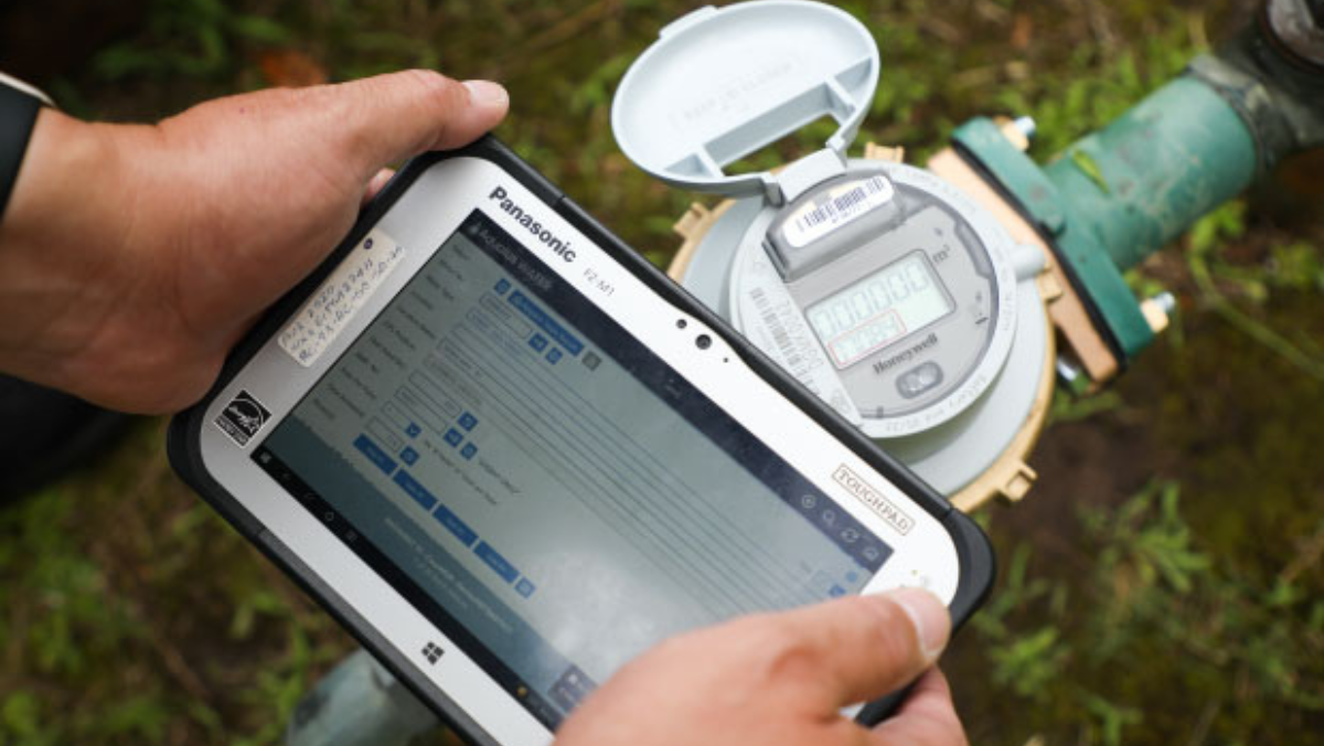 Technician using tablet to check smart water meter during field inspection