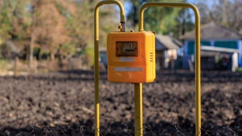 Yellow smart water meter installed outdoors on a metal frame near rural land