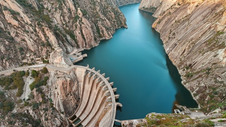 Aerial view of a large dam and reservoir set between rocky cliffs